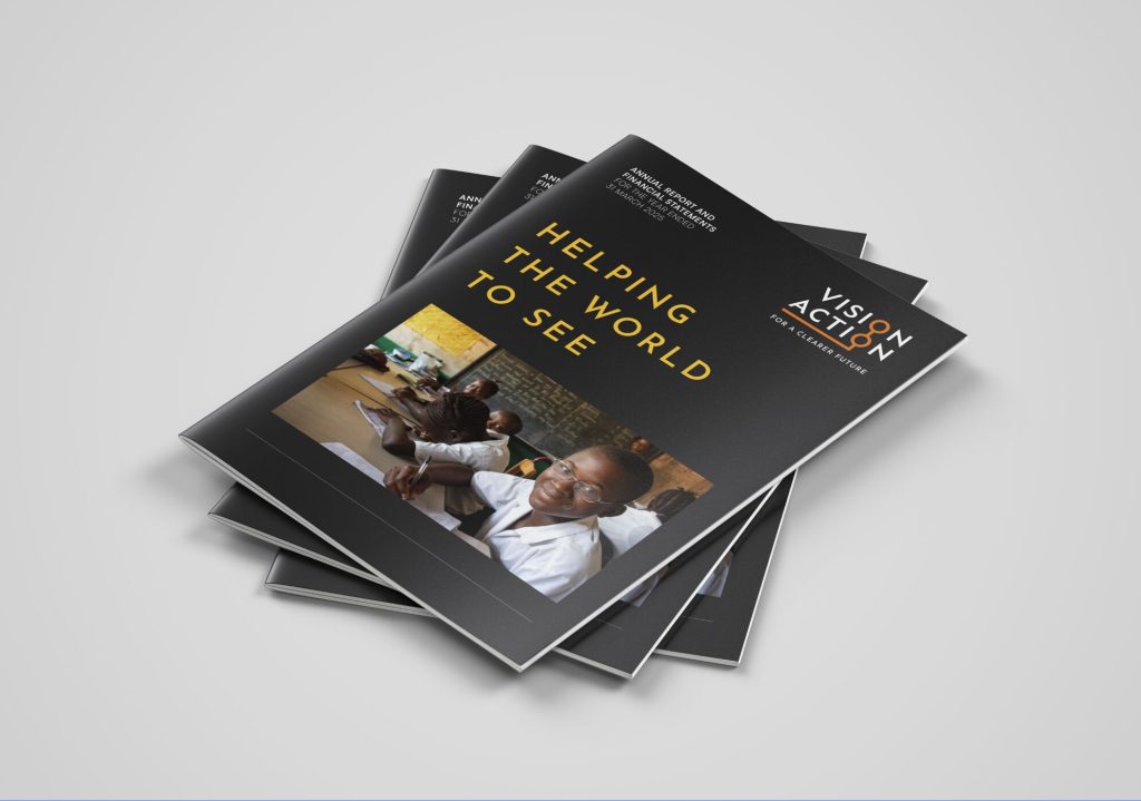 A stack of Vision Action annual reports designed by Mike Young, on a plain background