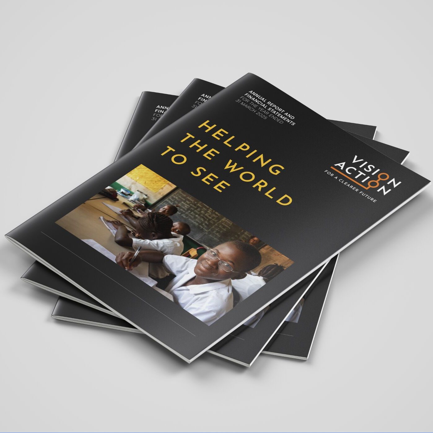 A stack of Vision Action annual reports designed by Mike Young, on a plain background