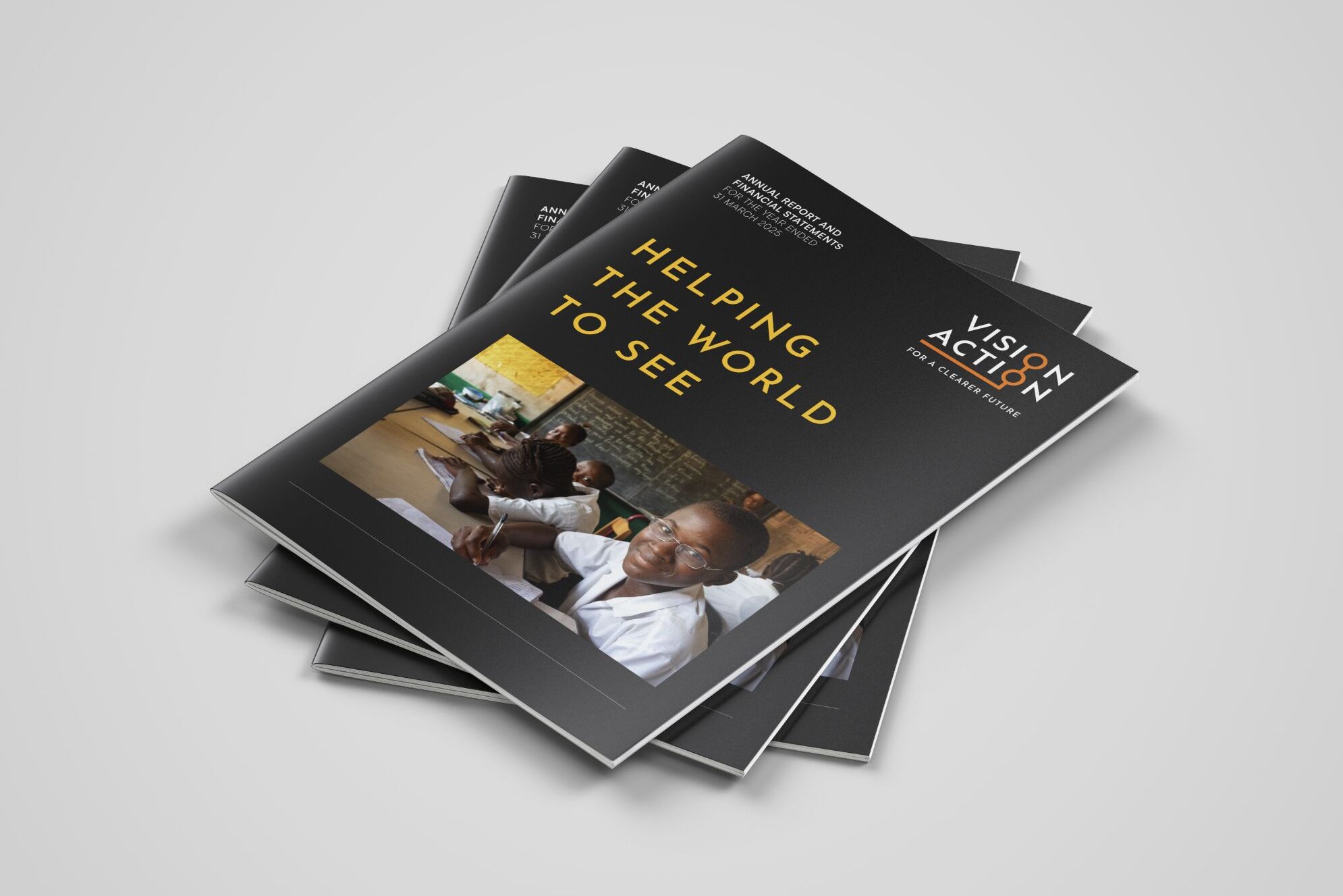 A stack of Vision Action annual reports designed by Mike Young, on a plain background